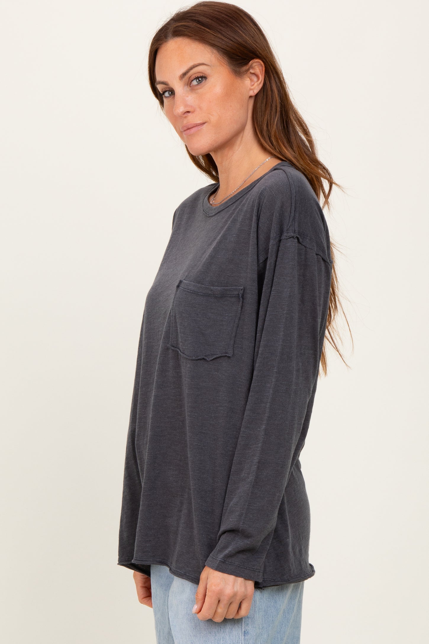 woman wearing a dark gray long sleeve top with a chest pocket and relaxed fit