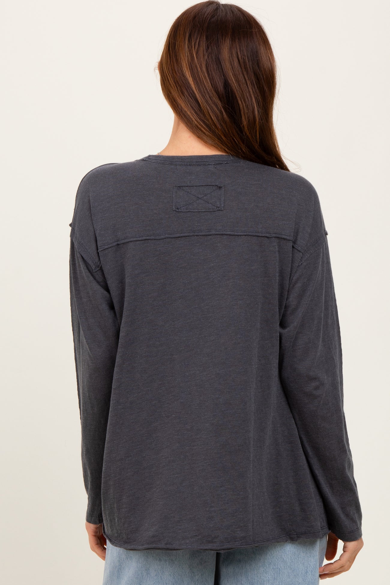 woman wearing a charcoal gray long sleeve top with a relaxed fit and back patch detail