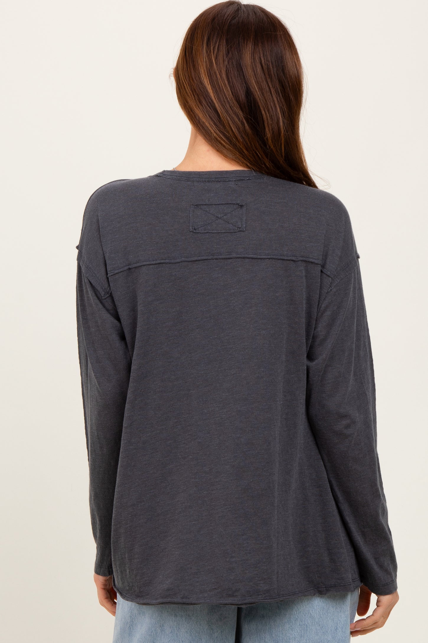 woman wearing a charcoal gray long sleeve top with a relaxed fit and back patch detail