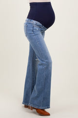 woman wearing a navy blue maternity belly band with flared light wash maternity jeans and a visible baby bump