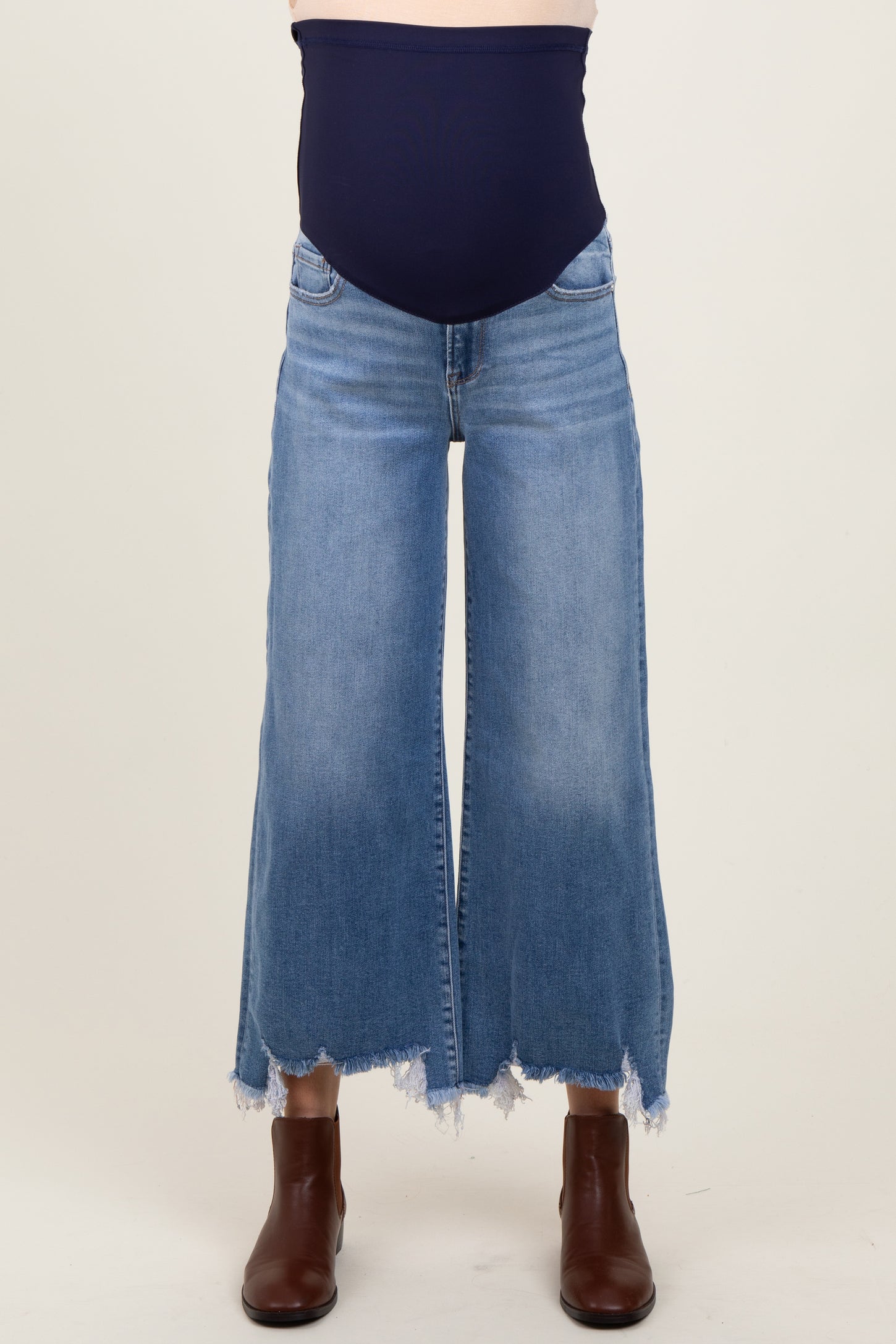woman wearing a pair of light blue maternity wide-leg jeans with a frayed hem and a navy belly panel