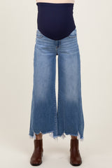 woman wearing a pair of light blue maternity wide-leg jeans with a frayed hem and a navy belly panel