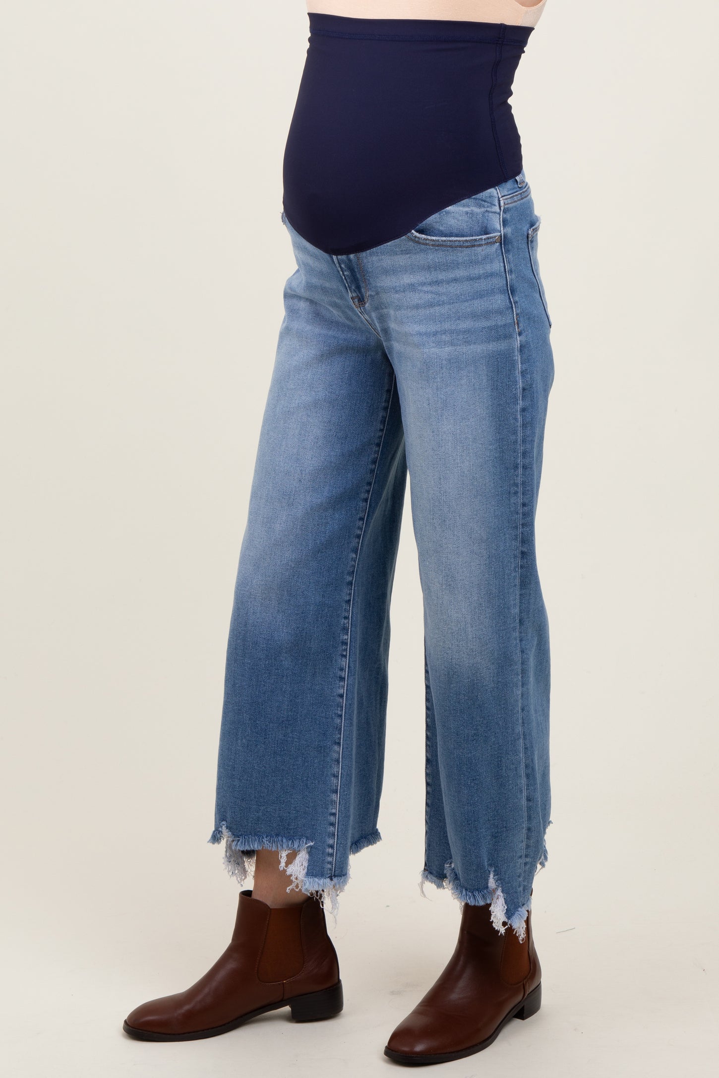 maternity wear, light wash denim wide leg jeans with a navy belly panel and frayed hem, model wearing brown ankle boots