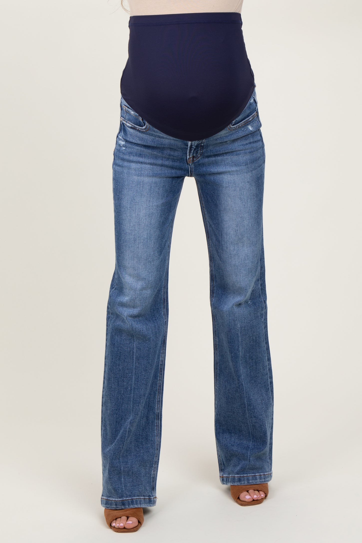 woman wearing dark blue maternity flared jeans with a supportive over-the-bump waistband and visible baby bump