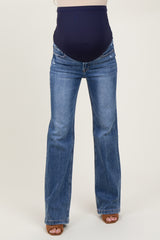 woman wearing dark blue maternity flared jeans with a supportive over-the-bump waistband and visible baby bump