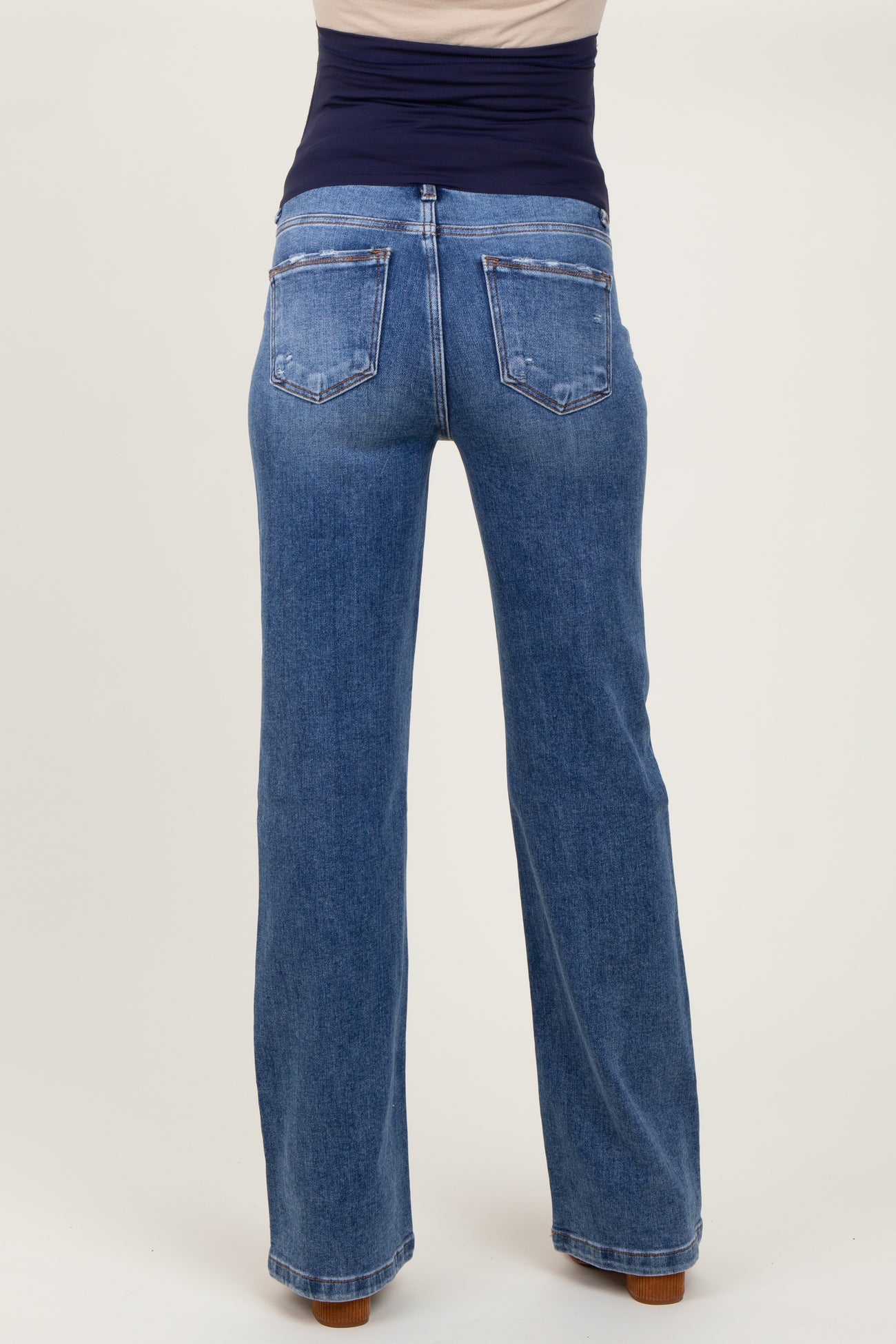 woman wearing light blue maternity jeans viewed from the back, featuring a wide leg style and a high waistband