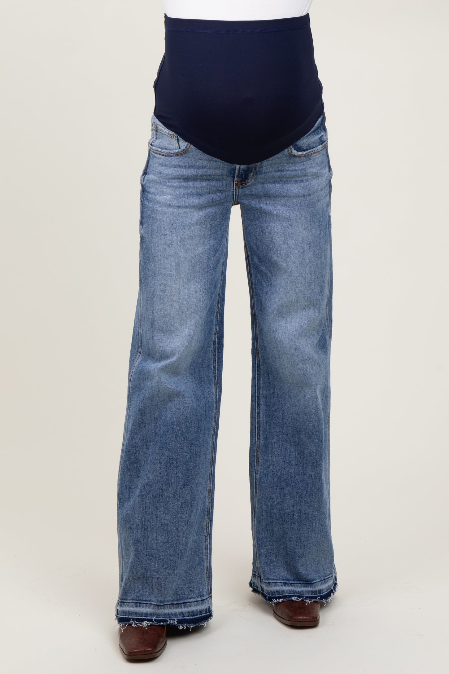 woman wearing a pair of light blue maternity flared jeans with a navy blue over-the-bump waistband