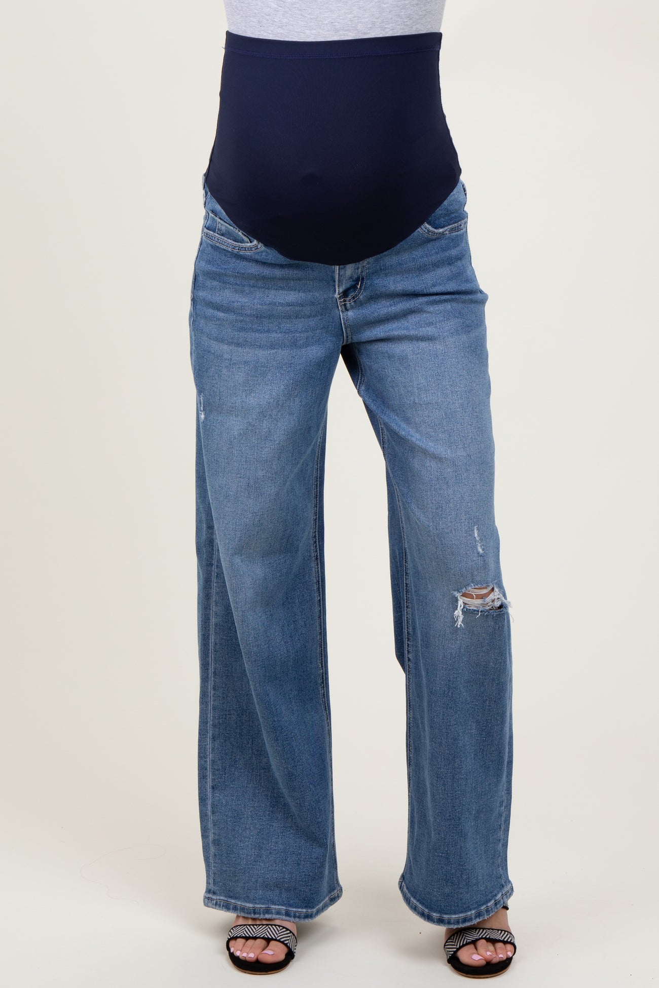 woman wearing maternity light blue wide-leg ripped jeans with a navy blue belly support band