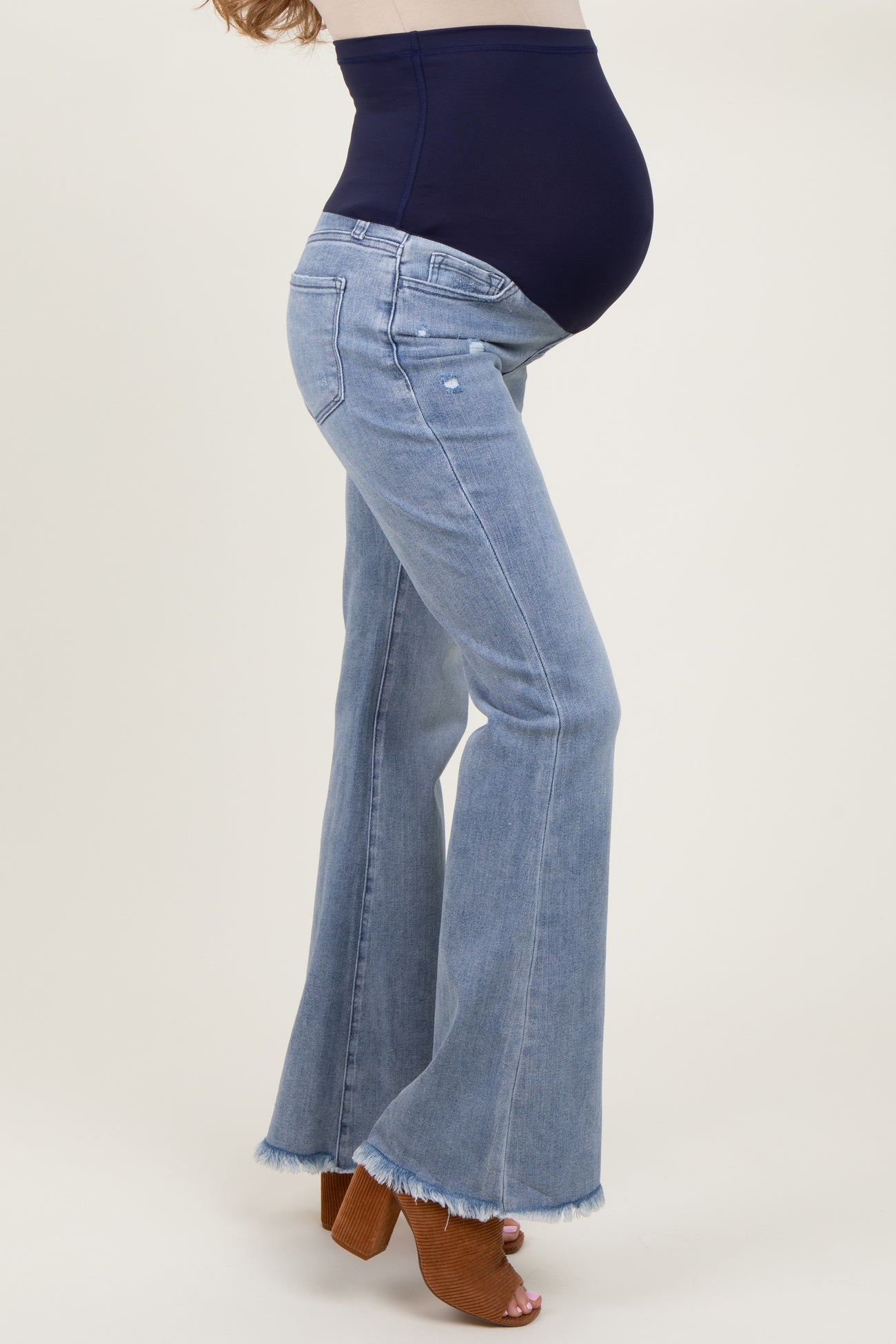 woman wearing light blue maternity flared jeans with a dark blue panel and a visible baby bump