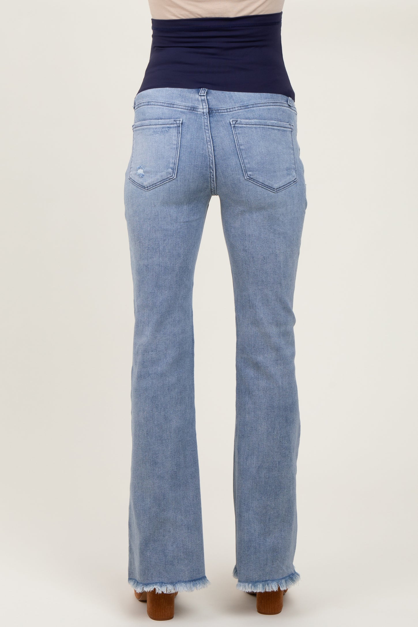 woman wearing light wash maternity jeans with a frayed hem and a stretchy waistband, showing the back view