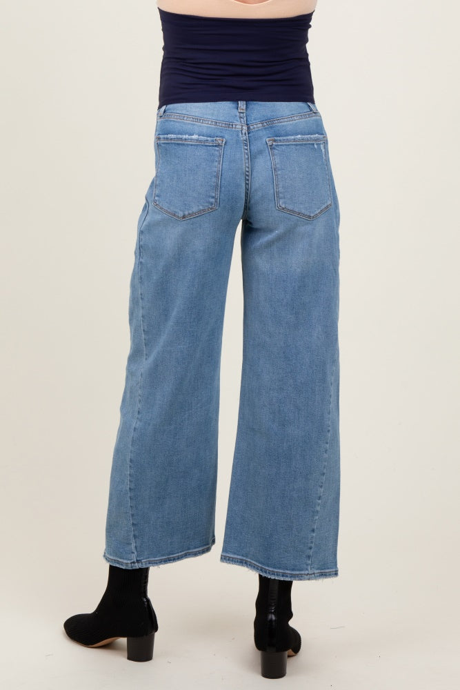 woman wearing light blue maternity wide-leg jeans, viewed from the back, with a fitted top and ankle boots
