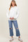 woman wearing a white ribbed maternity hoodie and distressed light wash jeans, holding her baby bump