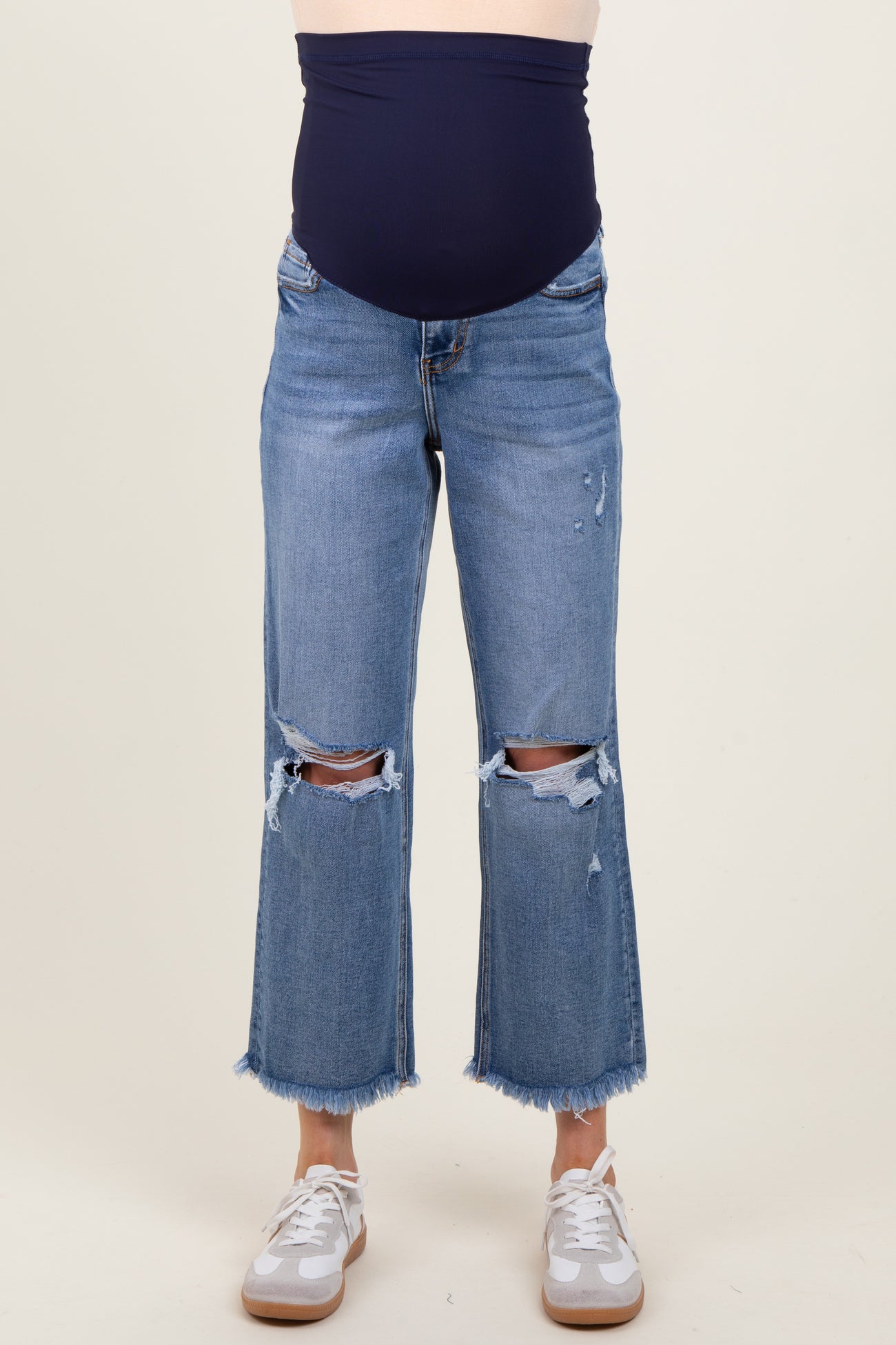 woman wearing a navy maternity belly band with distressed cropped jeans and white sneakers