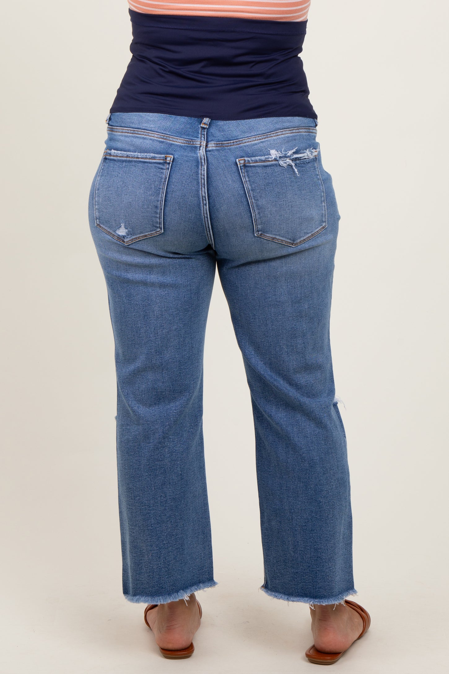 woman wearing a pair of distressed light blue maternity plus jeans with a flared leg and visible back pockets