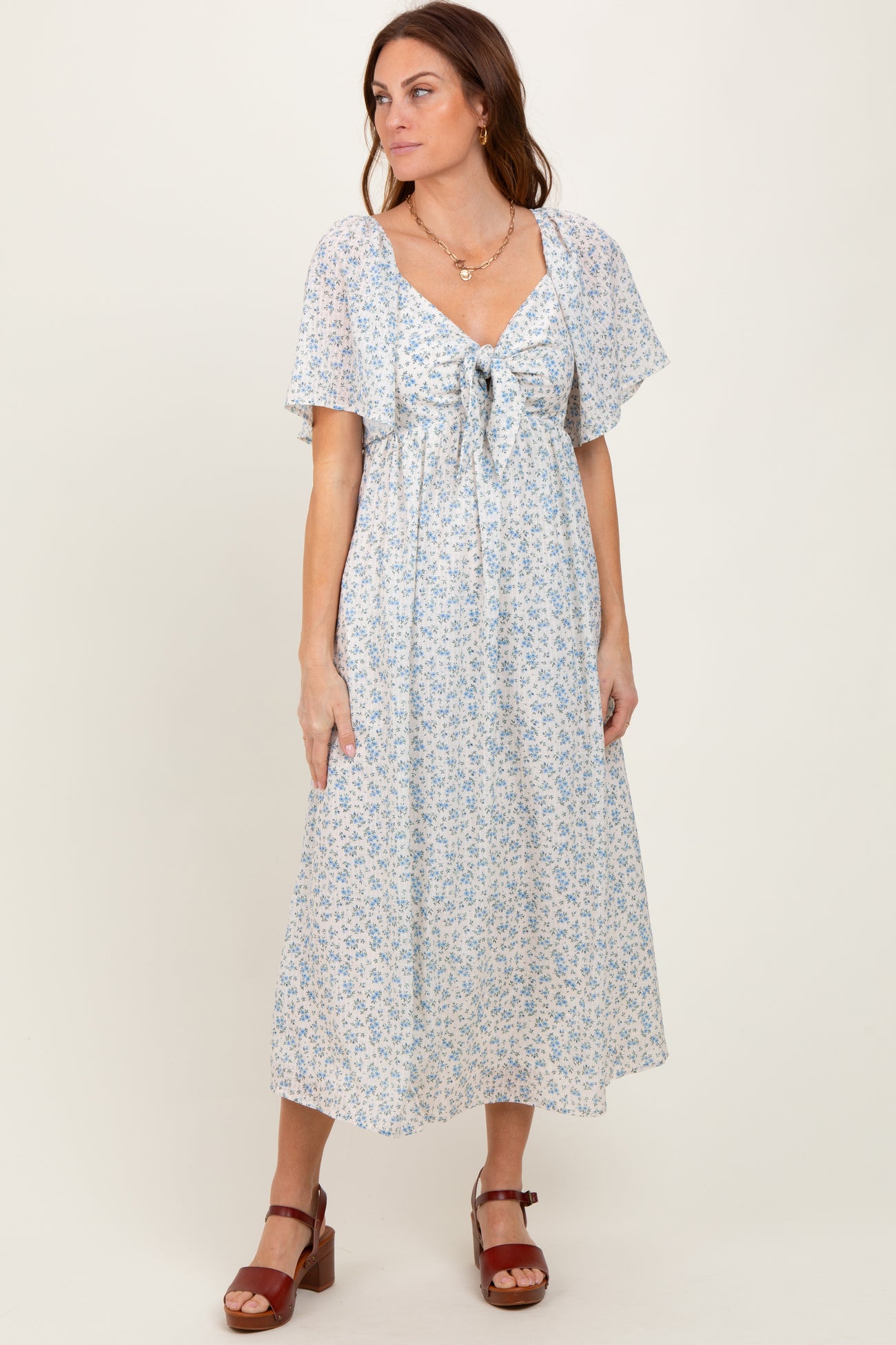 woman wearing a light blue floral maxi dress with a tie front and flutter sleeves