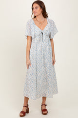 woman wearing a light blue floral maxi dress with a tie front and flutter sleeves