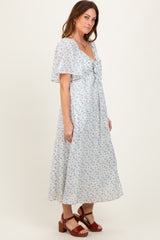 woman wearing a light blue floral maxi dress with short flutter sleeves and a tied neckline