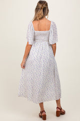 woman wearing a back view of a white floral smocked maternity dress with puff sleeves