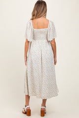 woman wearing a light floral maternity maxi dress with short puff sleeves and a square back