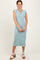 woman wearing a light blue ribbed midi dress with cap sleeves and side slit, smiling with hands on her hips