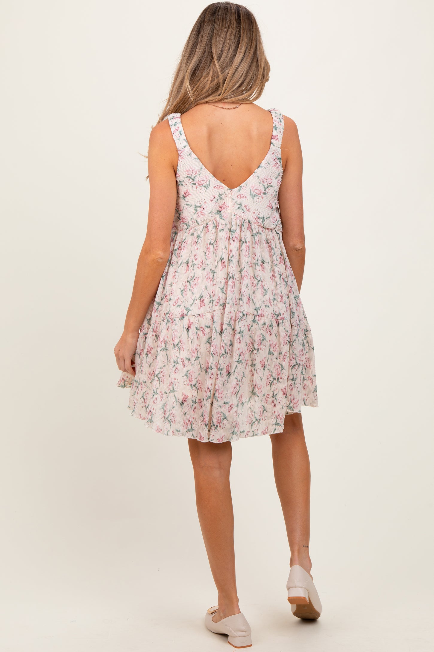 woman wearing a floral maternity dress with a scoop back and ruffled straps, showing a baby bump