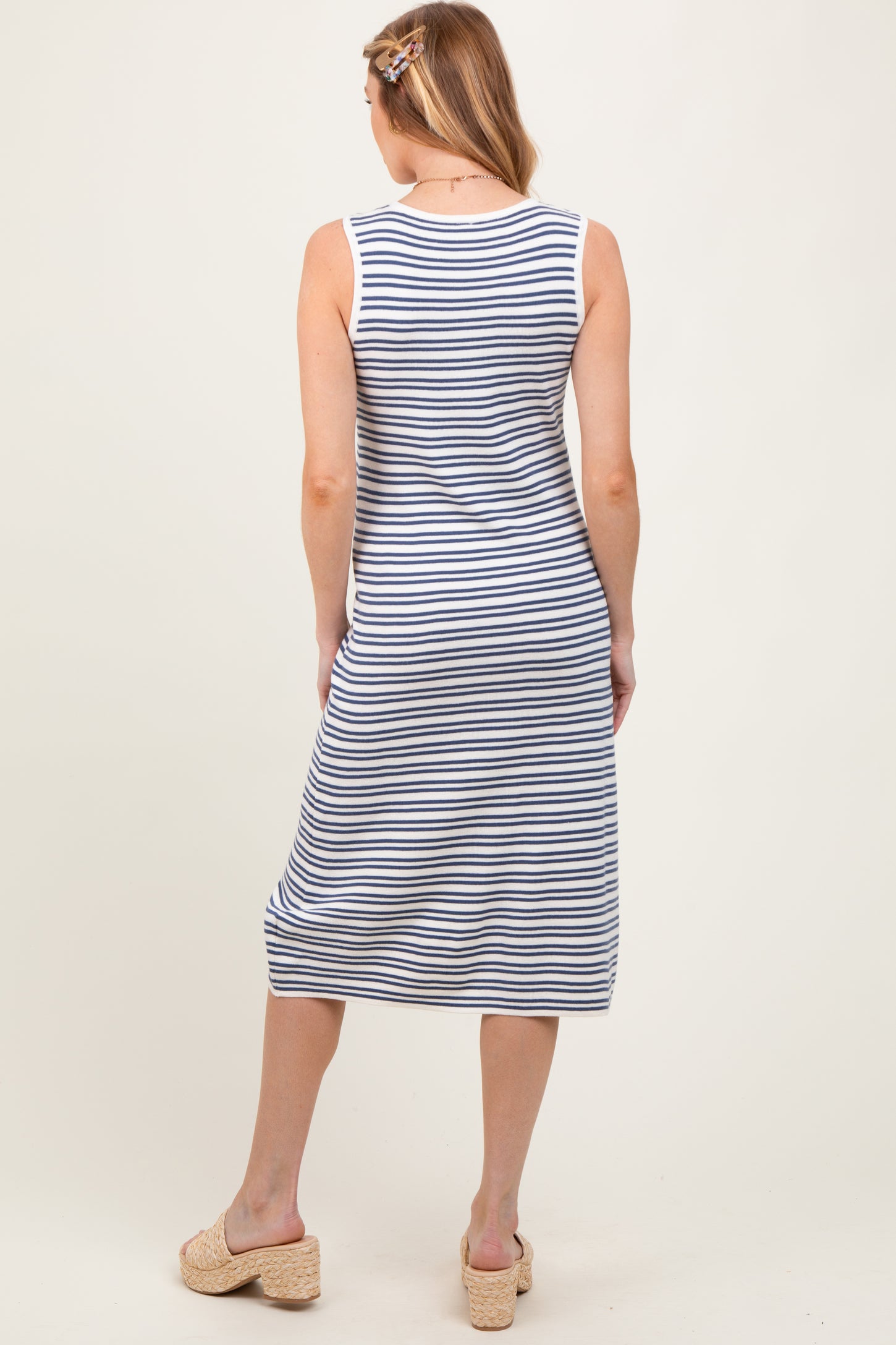 woman wearing a striped maternity sleeveless maxi dress standing with her back to the camera