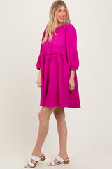 woman wearing a vibrant fuchsia puff sleeve dress with a tiered skirt and white sandals