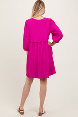 woman wearing a bright pink textured dress with three-quarter sleeves and a gathered waist, standing with her back to the camera