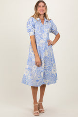 woman wearing a light blue floral midi dress with puff sleeves and a collar, standing and smiling