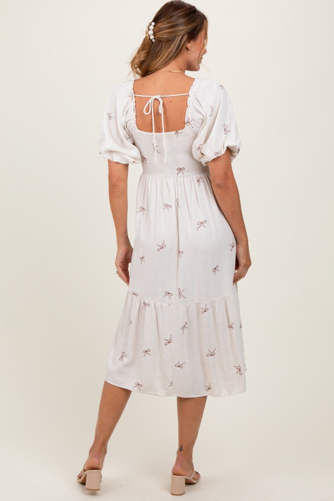 woman wearing a white midi dress with puff sleeves and a back tie detail, featuring a sweet bow print