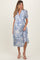 woman wearing a blue and white paisley print maternity dress with short sleeves and a tiered hem, showing her baby bump