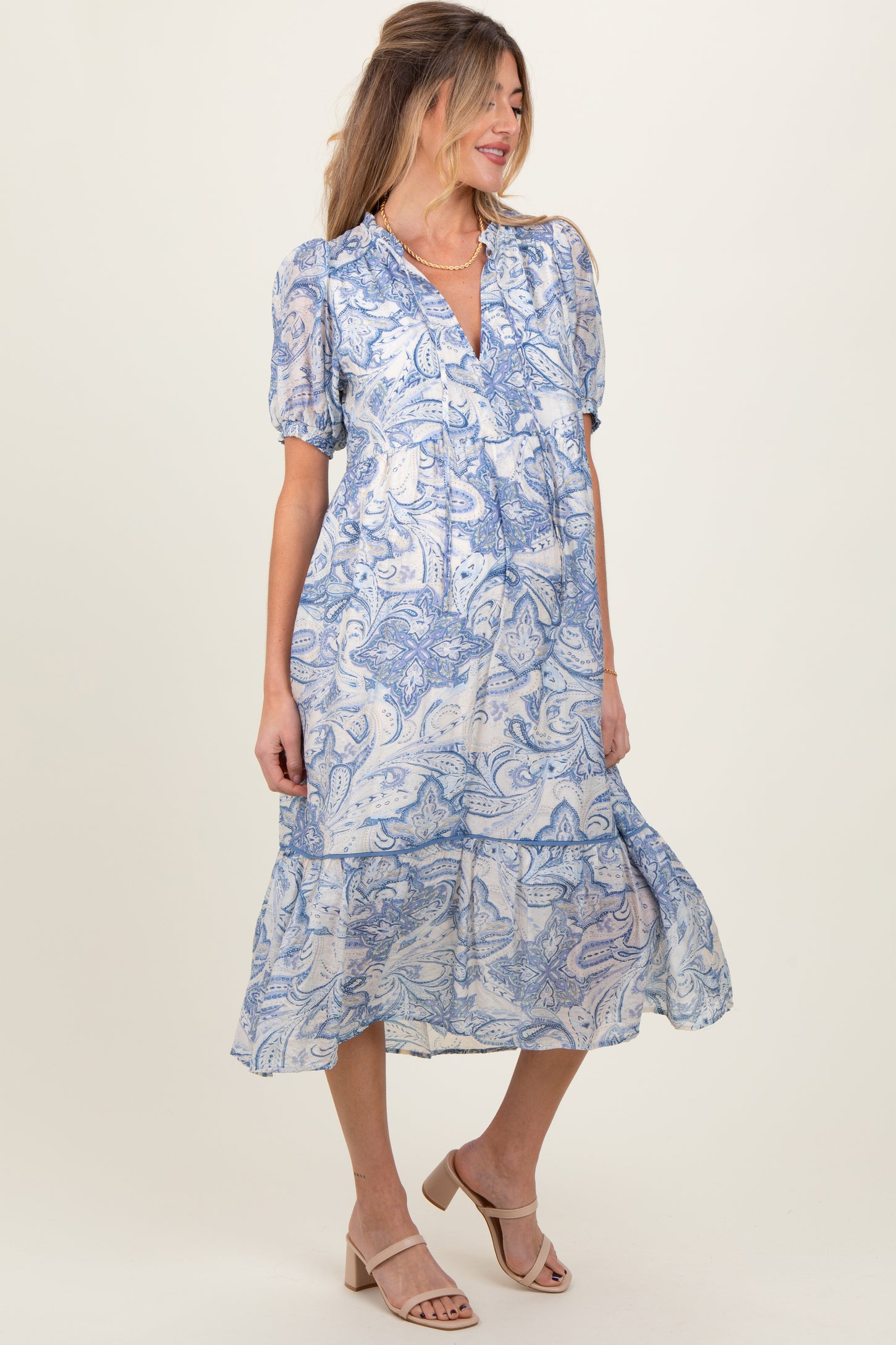 woman wearing a blue and white paisley print maternity dress with puff sleeves and a tiered skirt