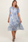 woman wearing a blue and white paisley print midi dress with puff sleeves and a tie neckline