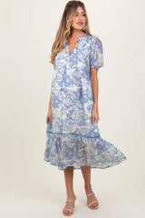 woman wearing a blue paisley print maternity dress with puff sleeves and a tiered hemline, showcasing her baby bump