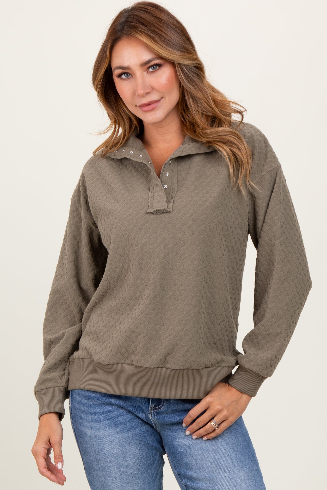 woman wearing a olive green textured pullover with a collar and button details, paired with blue jeans