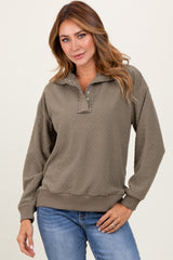 woman wearing a olive green textured pullover with a collar and button details, paired with blue jeans