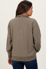 woman wearing a green quilted maternity jacket with a relaxed fit and ribbed cuffs, showing her back