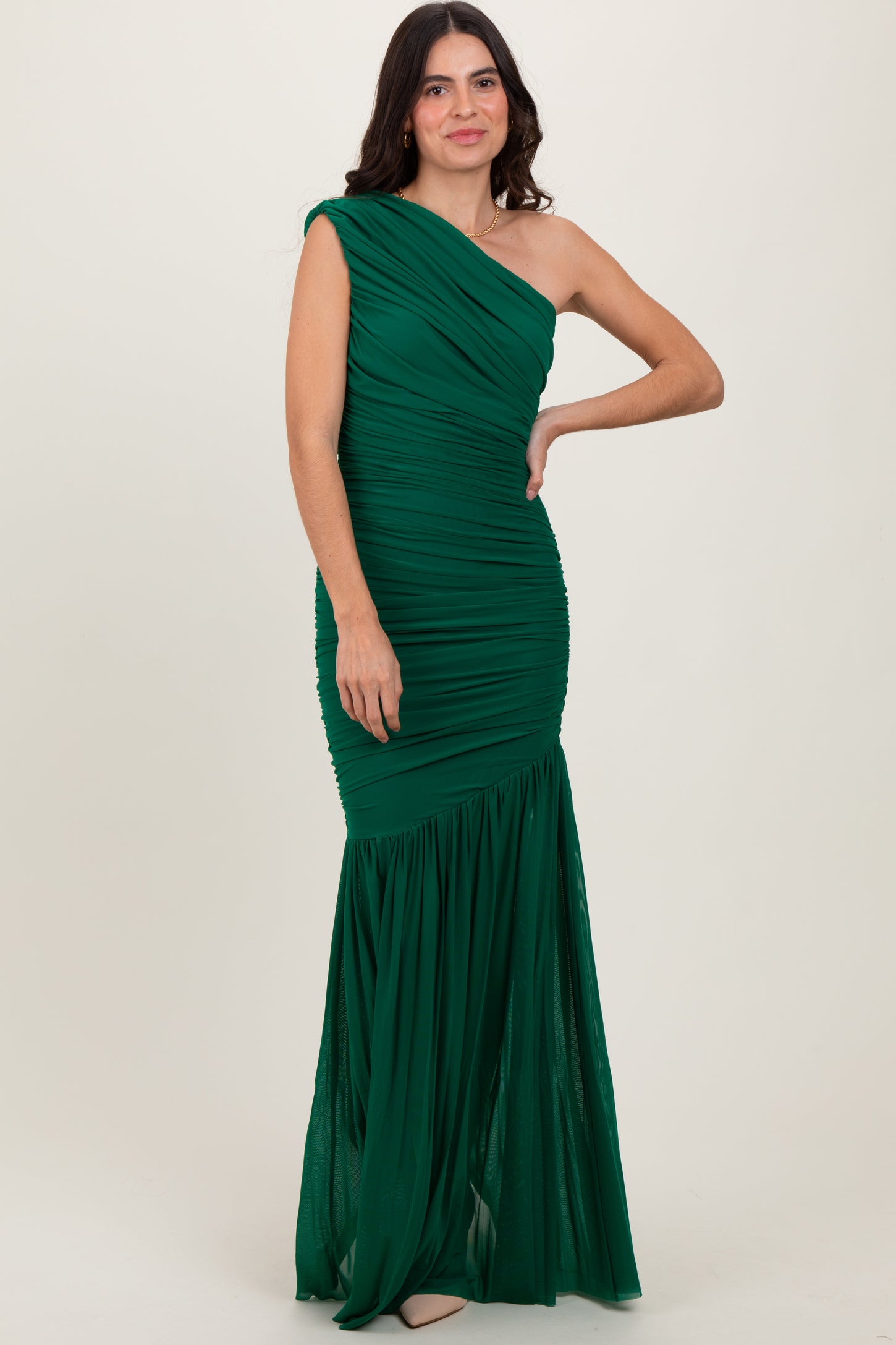 woman wearing a green one-shoulder evening gown with gathered detailing and a flared skirt