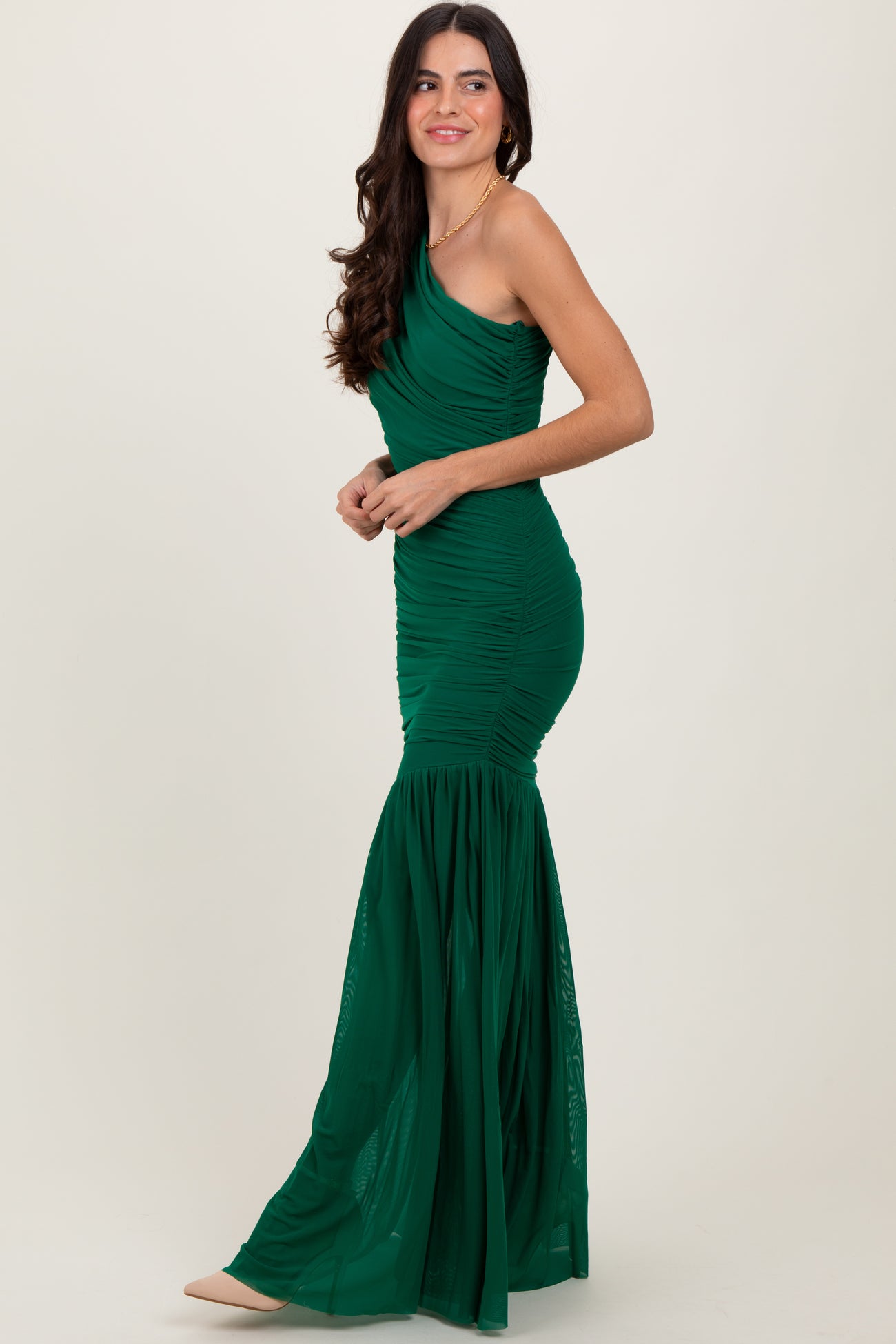 woman wearing a green one-shoulder evening gown with ruched detailing and a mermaid silhouette