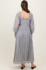woman wearing a light grey lace maternity dress with puff sleeves and a smocked bodice, shown from the back