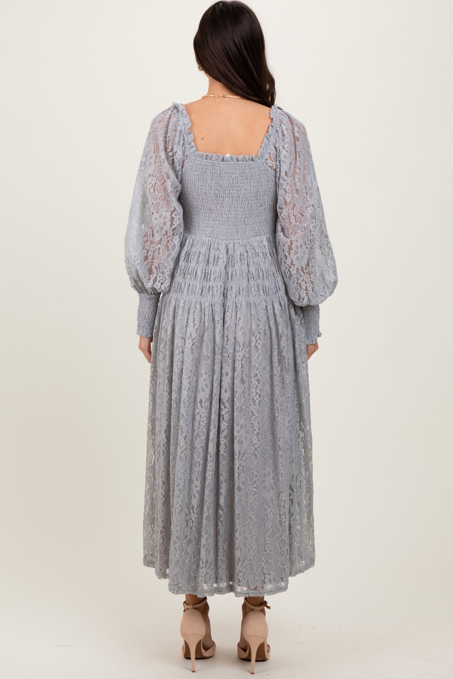woman wearing a light gray lace long sleeve dress with a smocked bodice and puff sleeves, view from the back