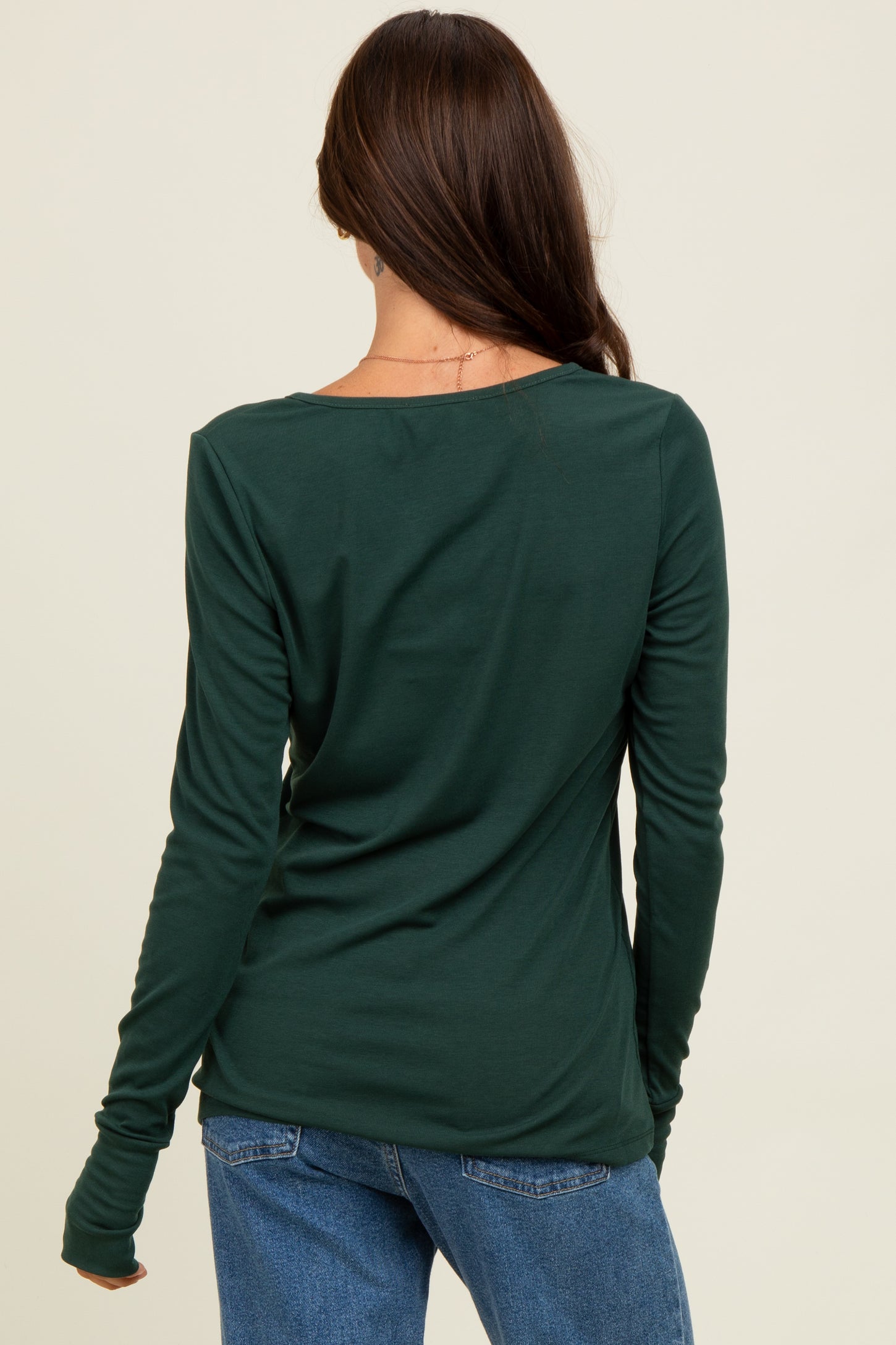 woman wearing a dark green long sleeve top with a scoop neckline, shown from the back