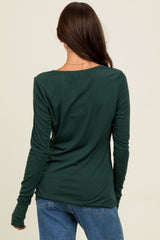 woman wearing a dark green long sleeve top with a scoop neckline, shown from the back