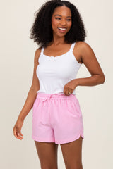 woman wearing a white lace-trimmed camisole and pink striped shorts with an elastic waistband