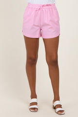woman wearing pink striped casual shorts with an elastic waistband and white slide sandals