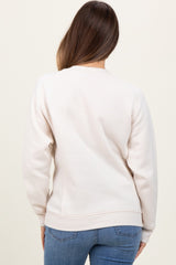 woman wearing a light beige maternity sweatshirt with a relaxed fit and ribbed hem, viewed from the back