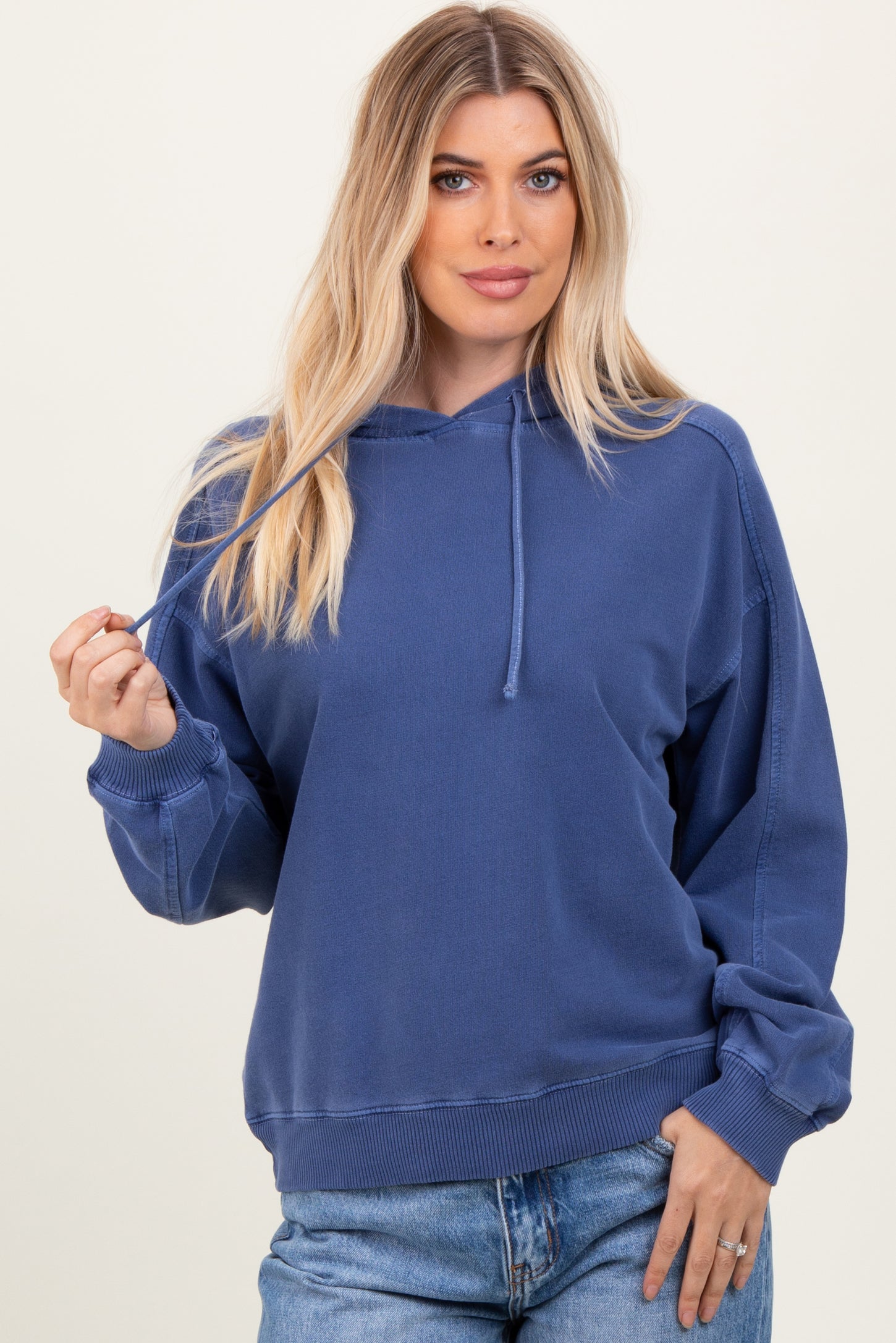 woman wearing a navy blue cropped hoodie with a drawstring and relaxed fit, paired with light blue jeans