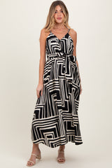 woman wearing a black and white geometric print maternity maxi dress with a tie waist and adjustable straps