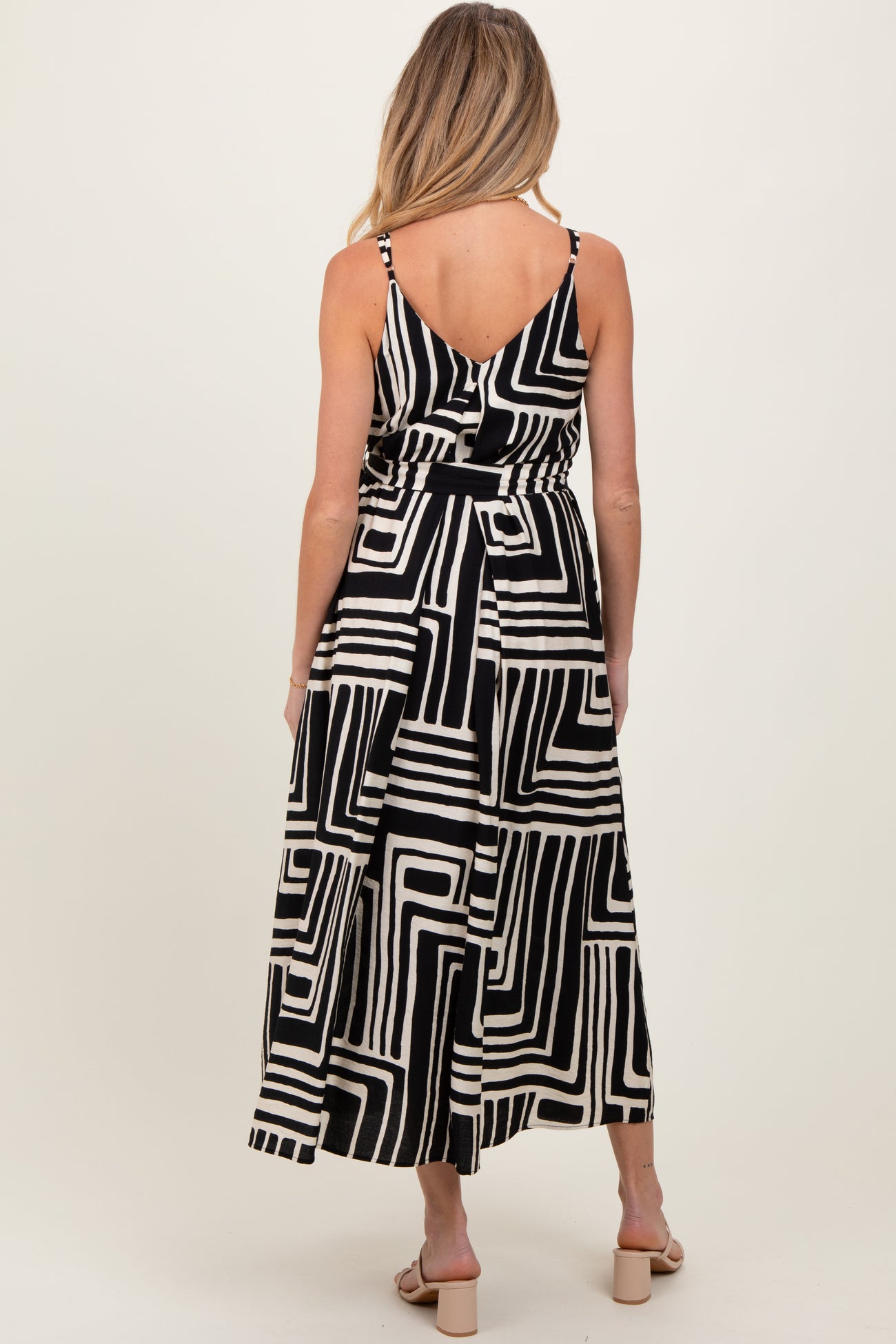 woman wearing a black and white geometric pattern maternity maxi dress, showing the back with adjustable straps