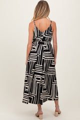 woman wearing a black and white geometric pattern maternity maxi dress, showing the back with adjustable straps